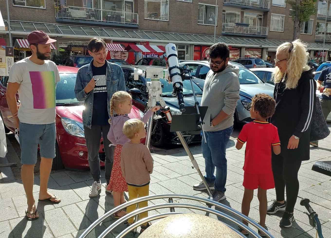 Foto van mensen verzameld rondom een telescoop