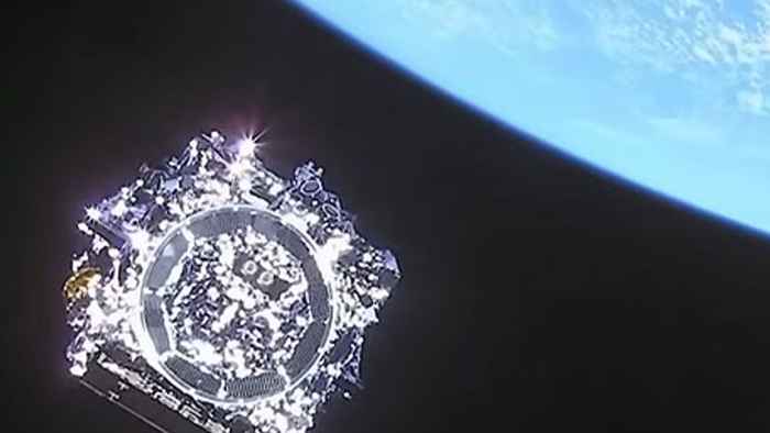 Picture taken from outer space of the James Web Space Telescope, a shiny cubic spaceship, and the earth in the top right.